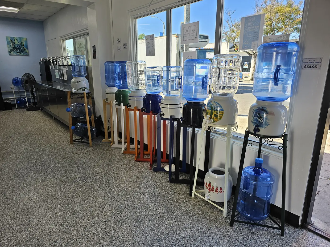 Glass and reusable water bottles, ceramic crocks and dispenser stands inside PB Water Store